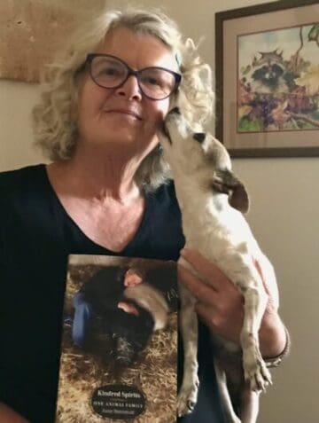 Anne Benvenuti, author, holding her dog and latest book, Kindred Spirits: One Animal Family